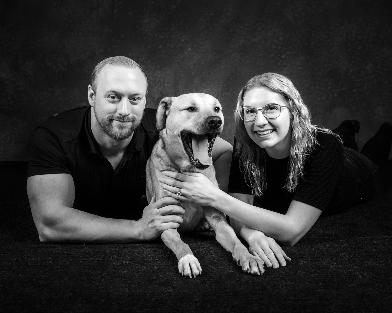 A couple lying on the floor with their laughing dog