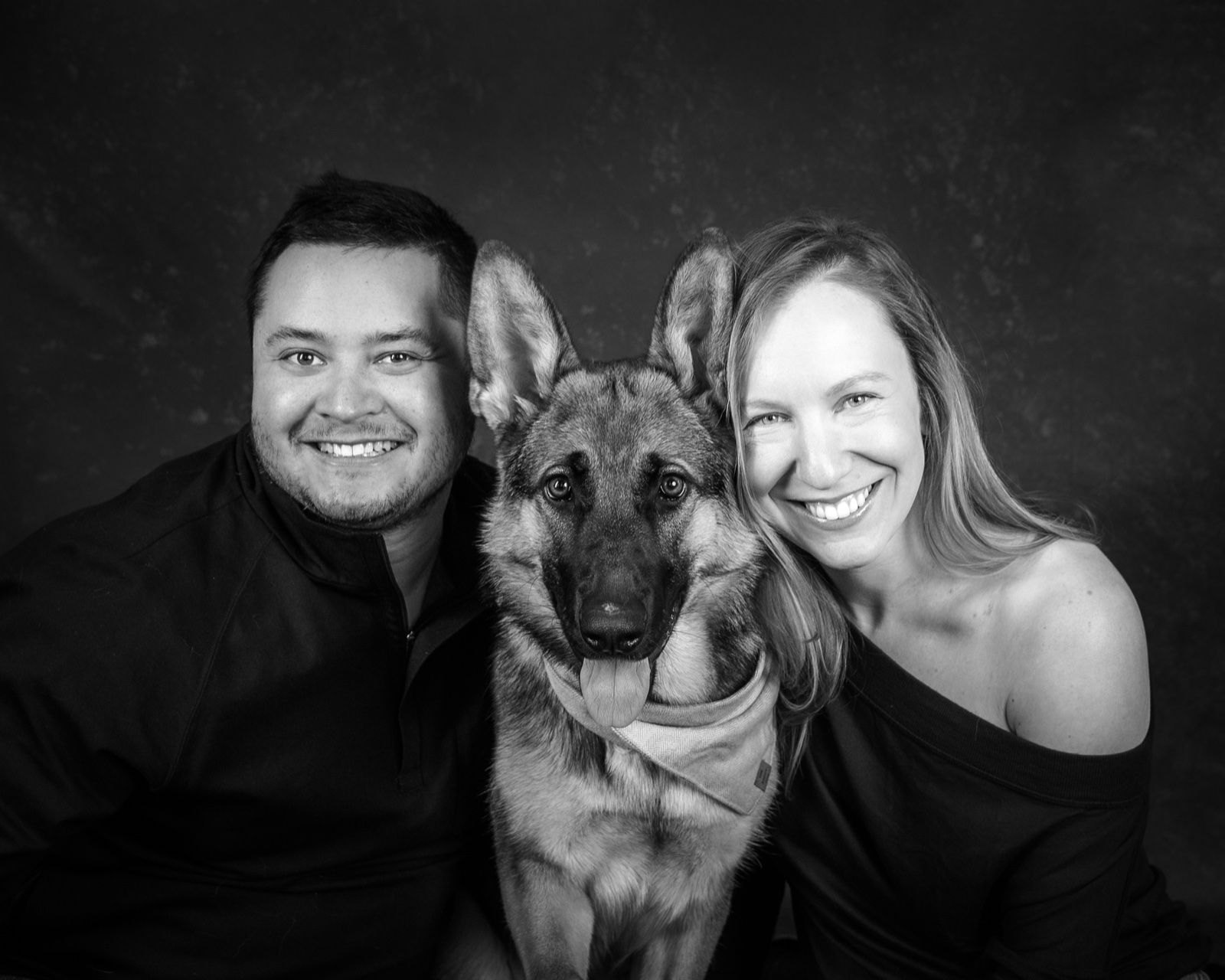 A couple with their German shepherd between them