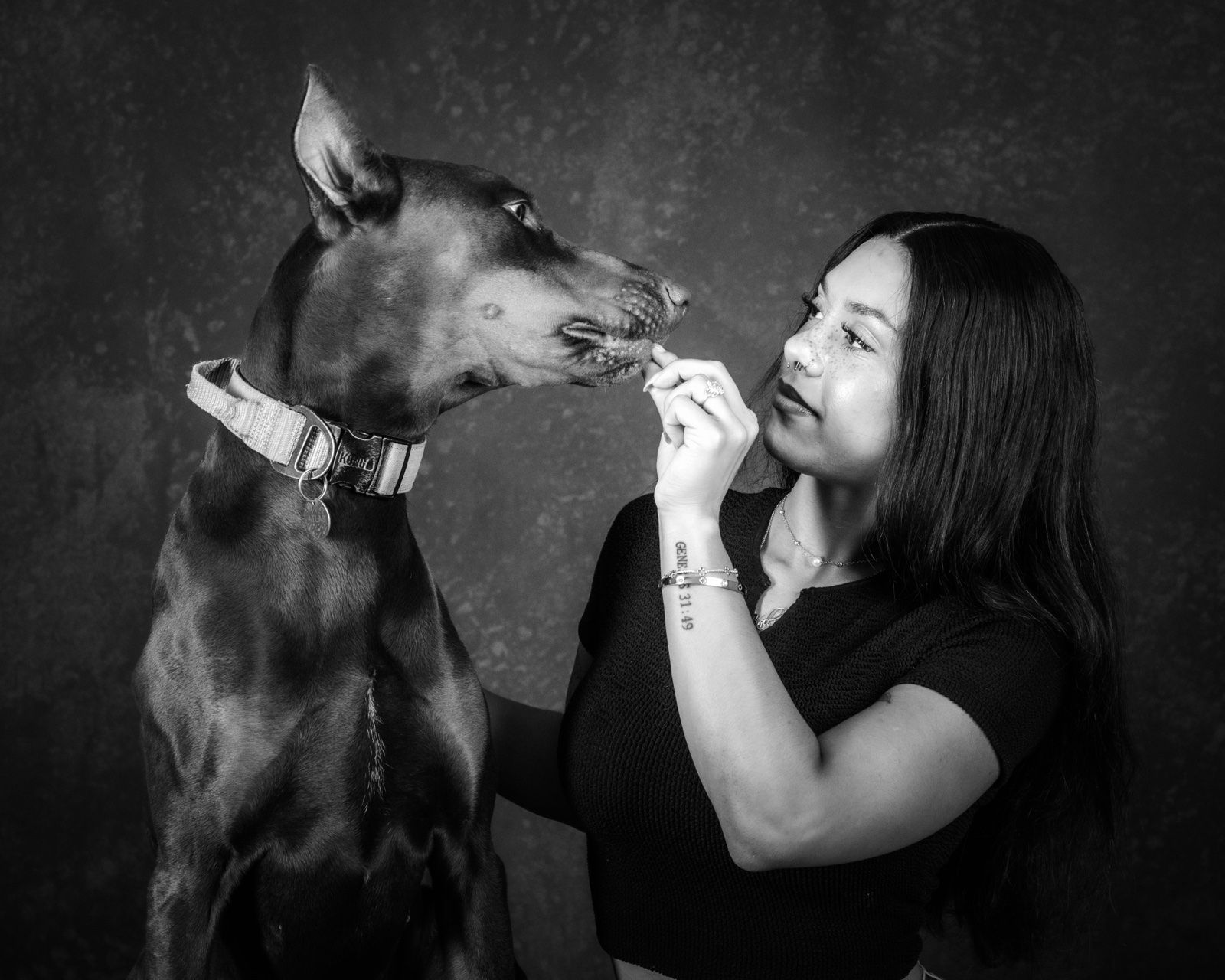 A Doberman licking a laughing woman's face