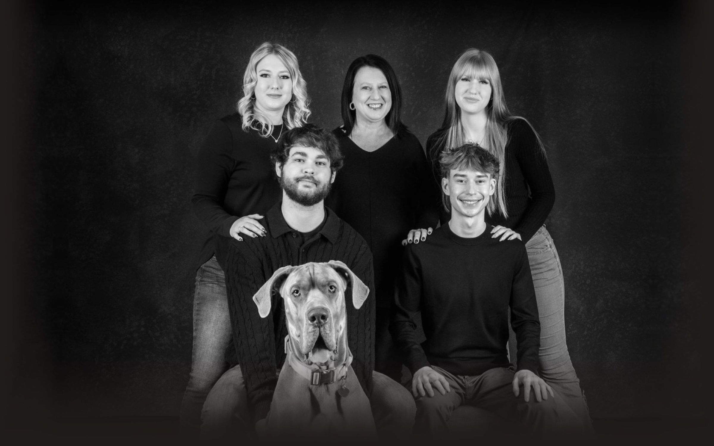 A family of five in black, with their Great Dane sitting in front