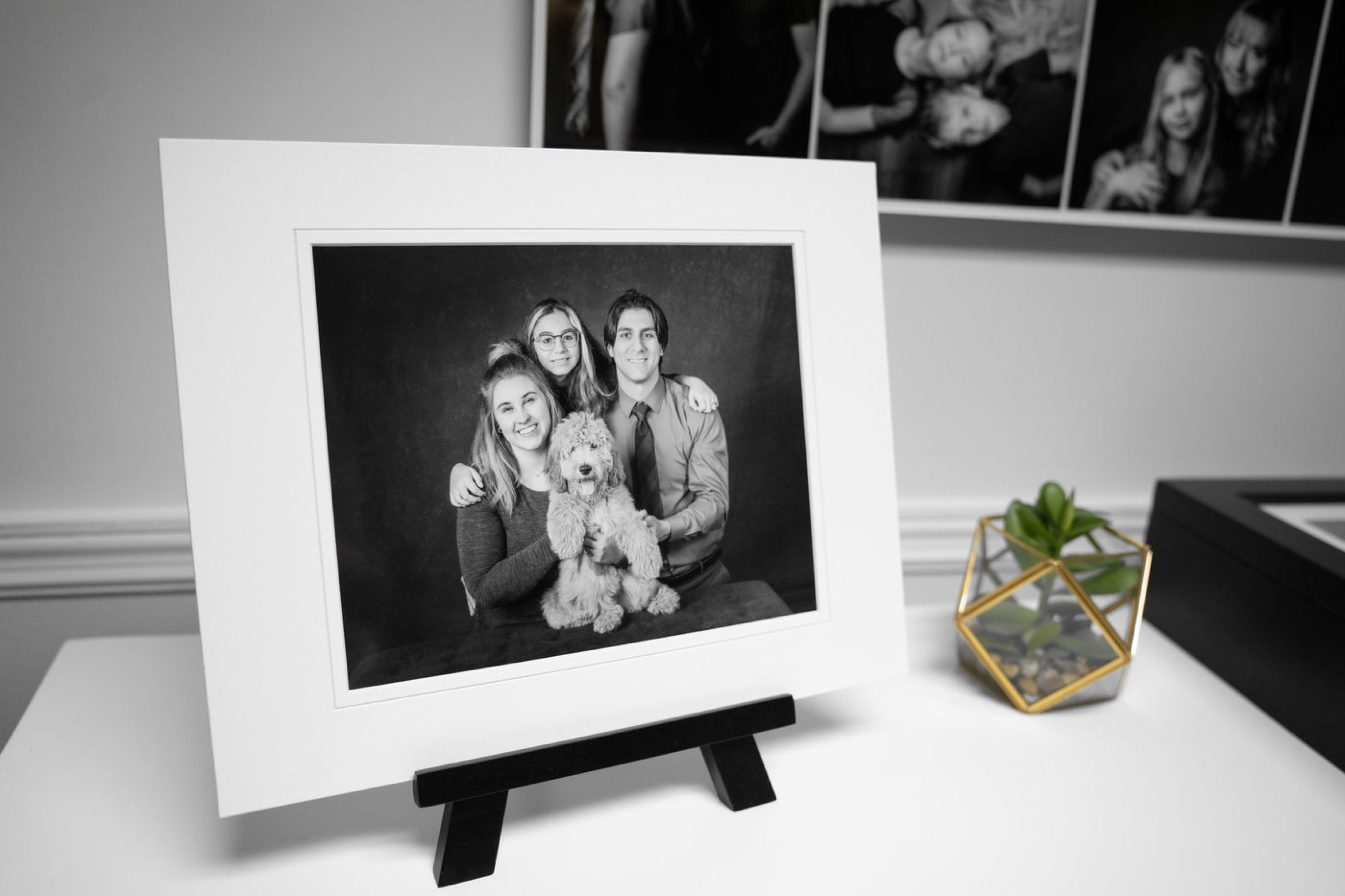 A matted black and white print of a family with their dog