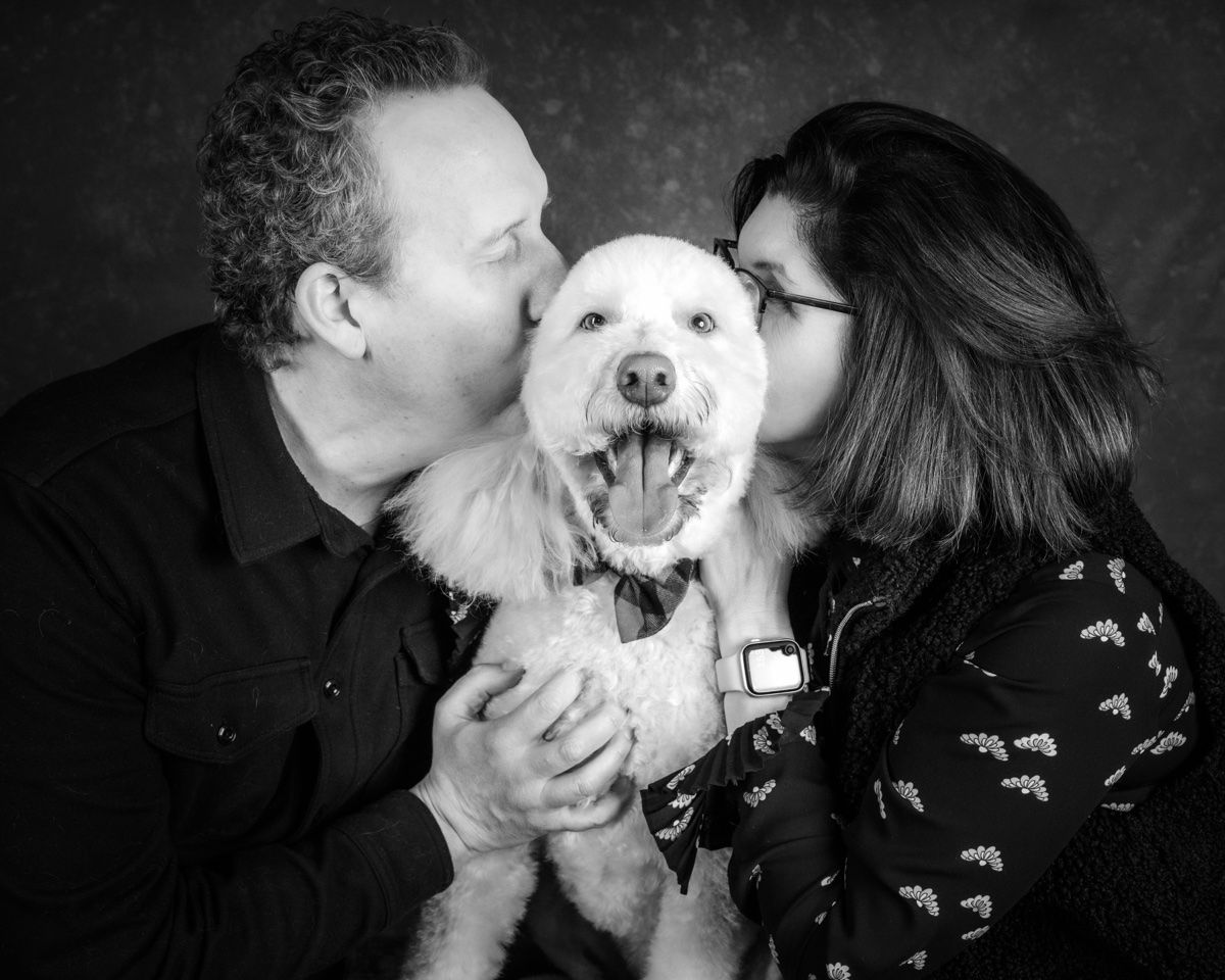 The couple kissing the poodle from both sides